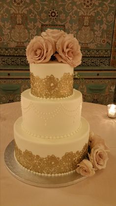 a three tiered wedding cake with pink flowers on top and gold trimmings