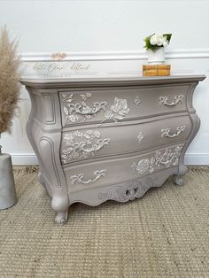 an antique dresser painted in silver with flowers on top