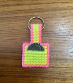 a pink and yellow keychain with a coin in it on a wooden table