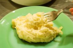 a fork with mashed potatoes on a green plate