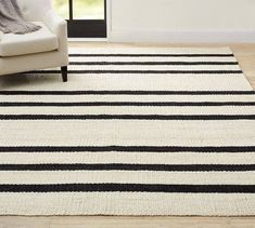 a white and black rug in a living room with a chair on the floor next to it