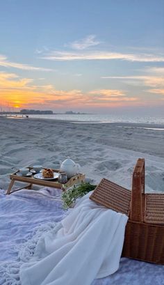 a wicker basket with food on the beach at sunset