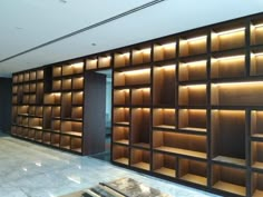 an empty room with wooden shelves and lights on the walls, along with marble flooring