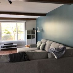 a living room filled with furniture and a flat screen tv mounted on a wall next to a window