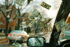 money is falling from the window of a car