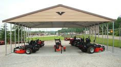 several lawn mowers are parked under a canopy