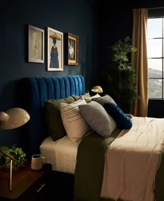 a bedroom with blue walls, green bedding and pictures on the wall above it