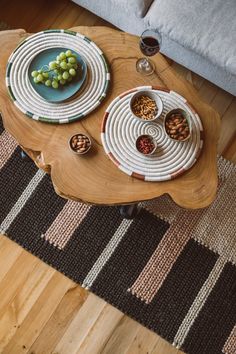 two plates with grapes and nuts sit on a coffee table