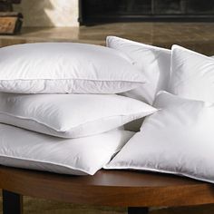 white pillows stacked on top of each other on a table in front of a fireplace