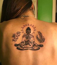 a woman with a tattoo on her back is sitting in a lotus position and meditates