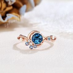 Inspired by the ethereal glow of the moonlight, this engagement ring is a combination of the 5mm round shaped London blue topaz and the moon motifs. The cluster moissanite and alexandrite shines with a mesmerizing glow, it creates a mesmerizing design that celebrates both the beauty of nature and the magic of romance.   Engagement Ring Detail  * Center stone: London Blue Topaz * Size: 5mm, round cut * Side stones: Moissanite & Lab Alexandrite * Shape: round shaped * Weight: 0.08ctw | D Color VVS Clarity * Band width: 1.6mm WHY IT WILL BE YOUR CHOICE  ❀ An exquisite jewelry gift with sentimental value for your cherished ones. ❀ Elegantly customized and prepared for any significant event. ❀ Crafted from ethically sourced and premium materials. ESSENTIAL INFORMATION 🚚: It usually takes 2-4 w Celestial Style Birthstone Ring, Celestial Style Round Sapphire Ring, Blue Celestial Moonstone Ring, Celestial Blue Round Moonstone Ring, Celestial Blue Moonstone Ring, Blue Moonstone Anniversary Ring, Blue Moonstone Ring For Anniversary, Celestial Wedding Ring, Moon Engagement Ring