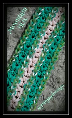 a green and white crocheted scarf on top of a gray blanket