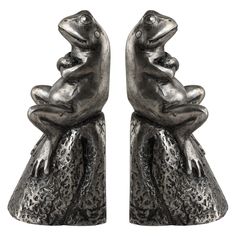 two silver frog figurines sitting side by side on top of each other,