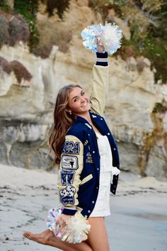 a beautiful young woman standing on top of a beach holding a pom - pom