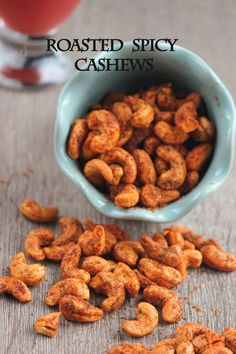 roasted spicy cashews in a blue bowl next to a glass of red liquid