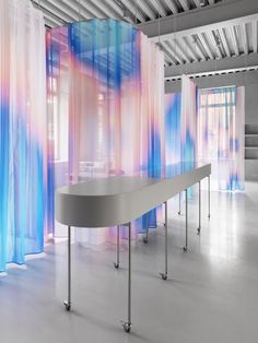 an empty room with blue and pink curtains on the walls, and a curved table in front of it