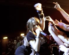 two young women singing into microphones in front of a group of people at a concert