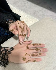 a woman with henna tattoos on her hands and fingers, sitting on a couch