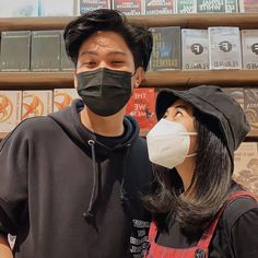 a man and woman wearing masks in front of bookshelves at a book store