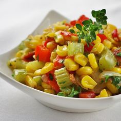 a white bowl filled with corn salad and garnished with parsley on top