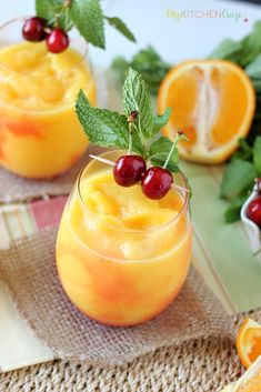 two glasses filled with orange juice and garnished with cherries