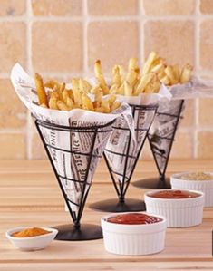 three cups filled with french fries sitting on top of a wooden table