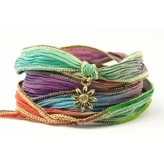 multicolored bracelets with gold charms and ribbons on white background, close up