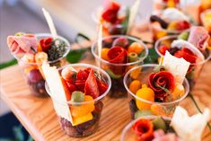 small cups filled with different types of fruit on a wooden table, ready to be served