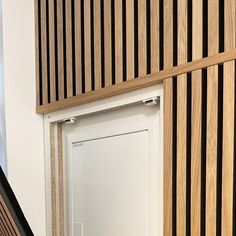 a white door sitting inside of a wooden room next to a wall with wood slats on it