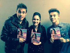 three people standing next to each other holding up magazines