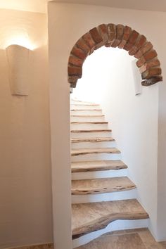 the stairs are made out of wood and have brick arches on each side, leading up to the second floor