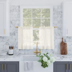 a kitchen with marble counter tops and white cabinets, along with a window over the sink