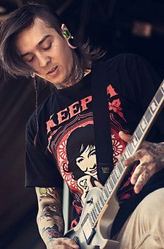 a man with long hair and piercings plays an electric guitar at a music festival