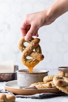 a person dipping some pretzels into a bowl