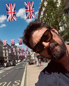 a man wearing sunglasses and headphones standing on the street with british flags in the background