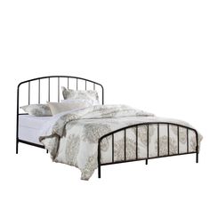 a black metal bed frame with white sheets and pillows