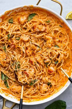 pasta with shrimp and tomato sauce in a large white bowl on top of a table