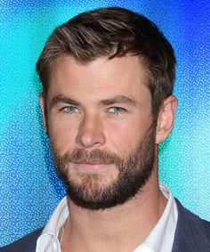 a close up of a person wearing a suit and white shirt in front of a blue background