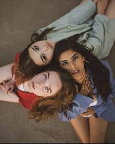 three women laying on the ground with their arms around each other and looking up at the camera