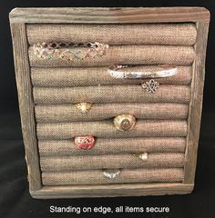 an old drawer with some rings and bracelets on the bottom, standing on edge, all items secure