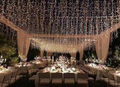 an outdoor dining area decorated with lights and chandeliers for a wedding or special event