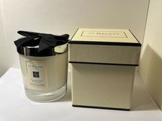 a candle with a black bow sitting next to a box on a white counter top