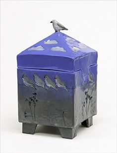 a blue box with a bird sitting on top of it's lid and the sky in the background