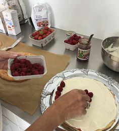 a person placing raspberries on top of a cake