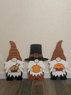 three wooden gnomes with hats on their heads