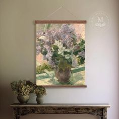 a painting hanging on the wall above a table with two vases and flowers in it