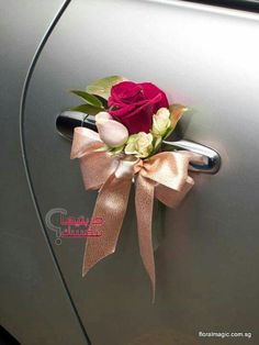 a car door handle with a rose and ribbon attached to the handle, as well as a bow