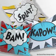 three pillows with comic speech bubbles on them, one saying bam kapow and the other saying splat