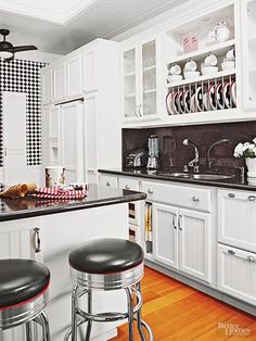 a kitchen with black and white checkered walls, wood flooring and stools