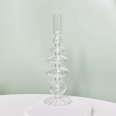 a tall clear glass candle holder sitting on top of a white table